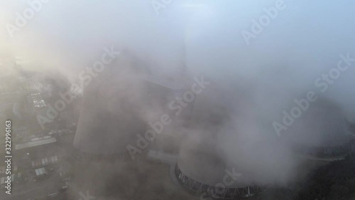 Aerial reveal view pull back UK power station cooling towers smoke steam emissions at sunrise.