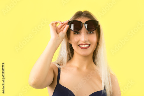 beautiful young woman in a swimsuit on a yellow background