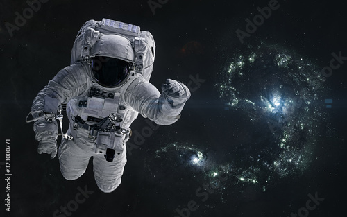 Astronaut on a background of colliding blue galaxies. Science fiction. Elements of this image furnished by NASA