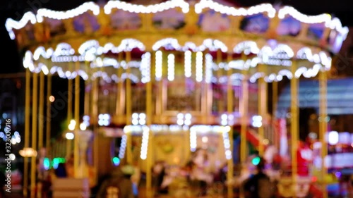 Christmas carousel blurred video. Bright carousel with lights and horses rolls the children. The video is out of focus for background.