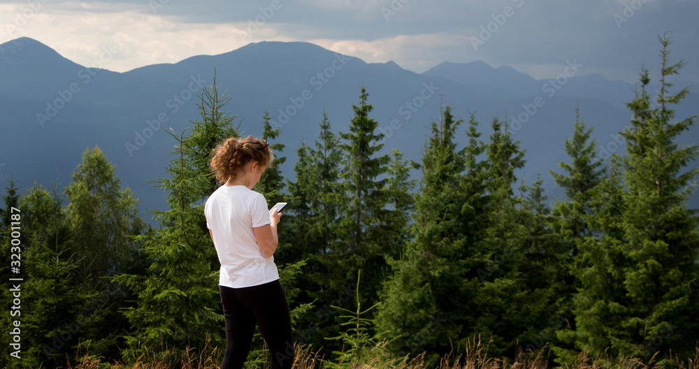 Young girl with mobile phone on mountains background_