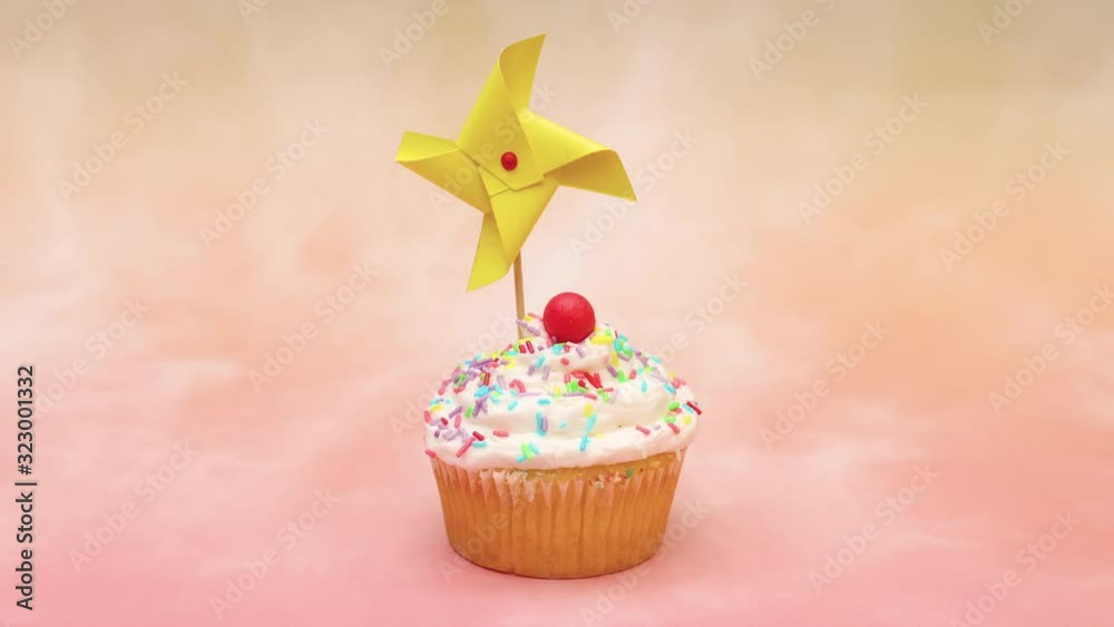 Decorative windmill moving on delicious party cup cake with white cream and red candy - Stop motion 