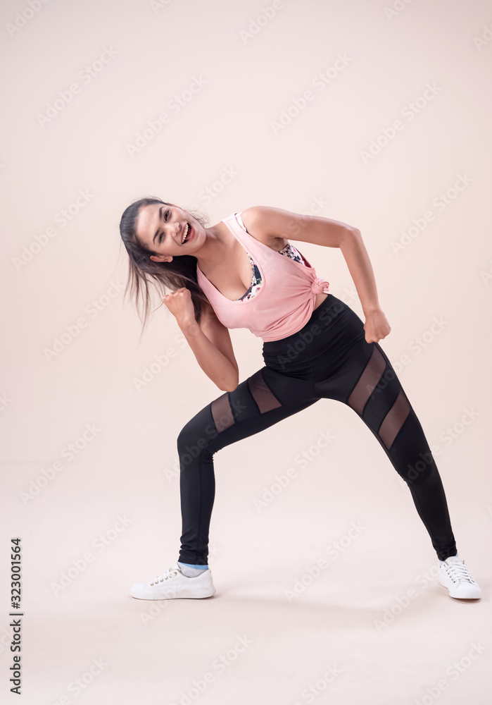 Young lady wearing exercise set outstretch her legs,twist body a little,flicking hair,fists down,show basic of dance workout,with happy feeling