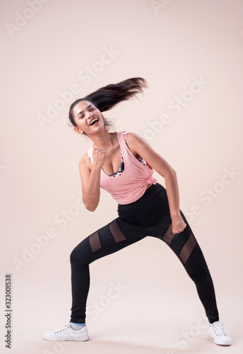 Young lady wearing exercise set outstretch her legs,twist body a little,flicking hair,fists up and down,,show basic of dance workout,with happy feeling
