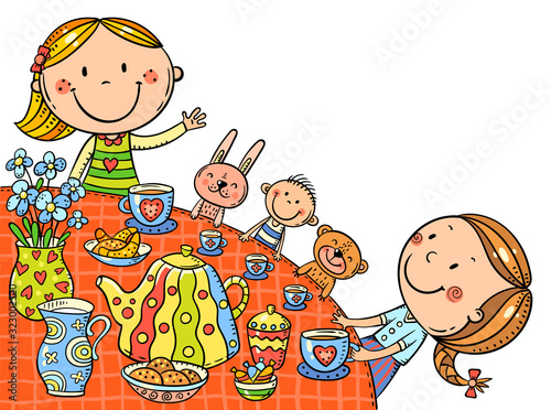 Little girls drinking tea at the table and playing with their toys