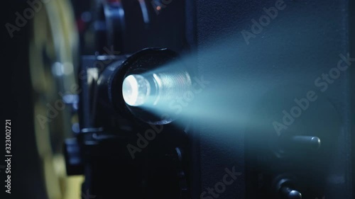 Close-up of a projector lens with a ray of light. Working 8mm retro film projector in a dark room