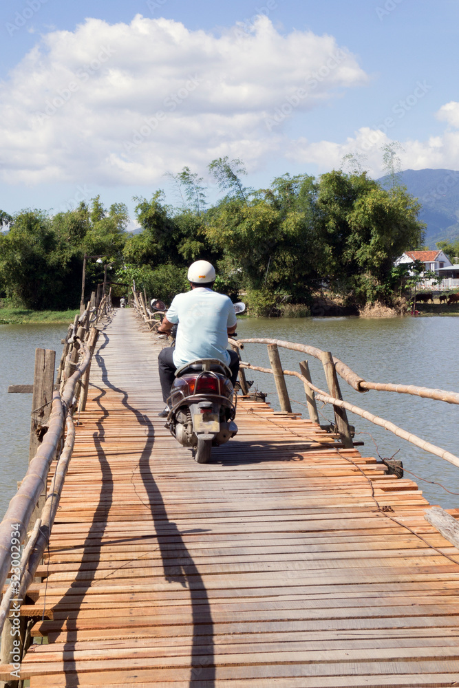man rides a motorcycle on a wooden bridge over the river man rides a motorcycle on a wooden bridge over the river