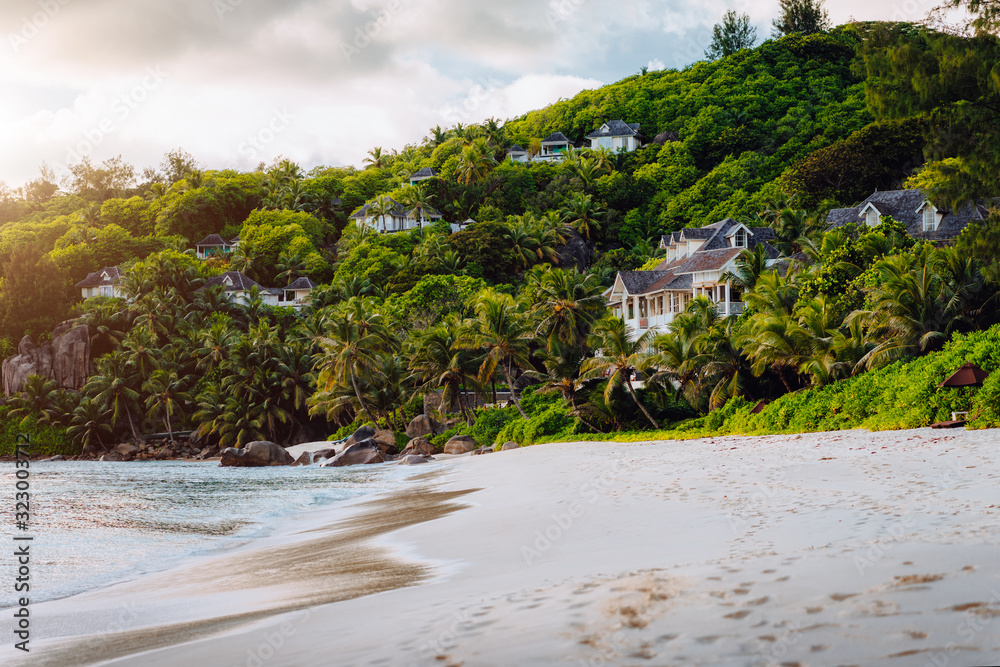 Mahe, Seychelles. Exotic tropical beach Anse Intendance in evening sunset light. Scenic view of luxury accommodation hidden in jungle