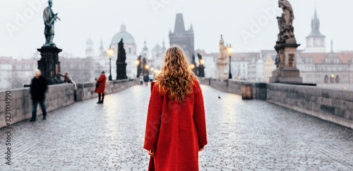 Fototapeta Female tourist walking alone on the Charles Bridge during the early morning in P