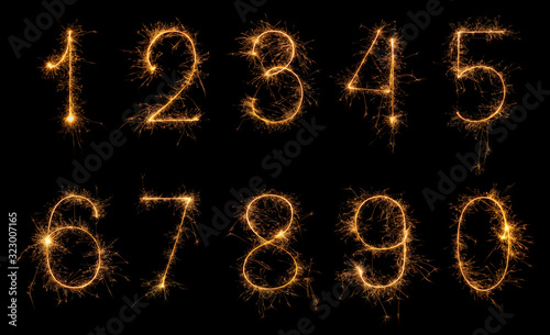 Set of burning sparkler numbers from 0 to 9 made of bengal fire, sparkler fireworks candle isolated on a black background. Party dark backdrop.