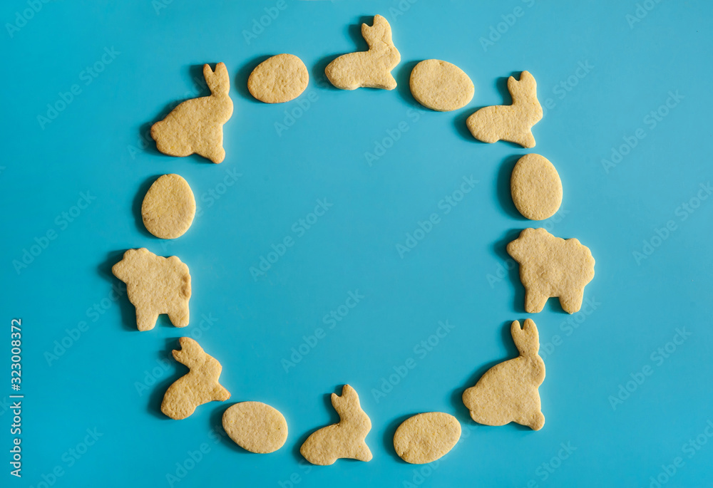 Easter composition. The wreath is made of homemade cookies in the form of Easter bunnies, eggs and lambs on a light blue background. Easter composition. The wreath is made of homemade cookies in the form of Easter bunnies, eggs and lambs on a light blue background.