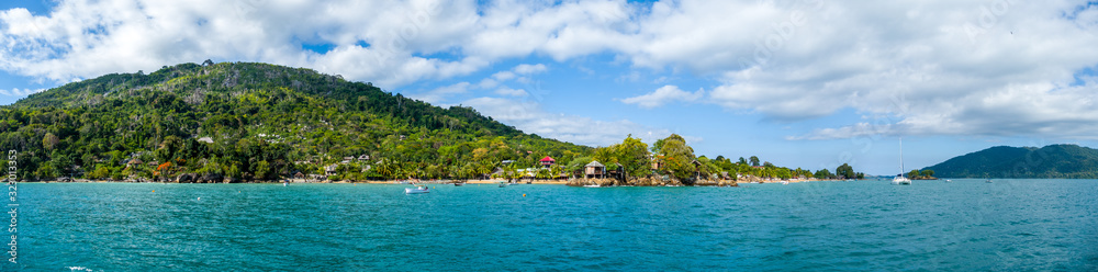 View of coastline on Nosy Komba Island lined with palm trees and , Madagascar close to Nosy Be