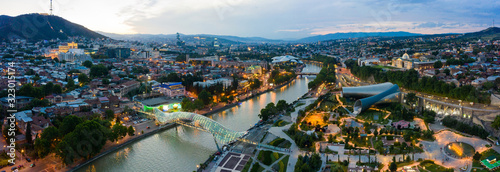 The evening panorama of the old town in the old district of Avlabari, Holy Trinity Cathedral and Rike Park, the Kura river reflects the evening city lights in Tbilisi, Georgia.