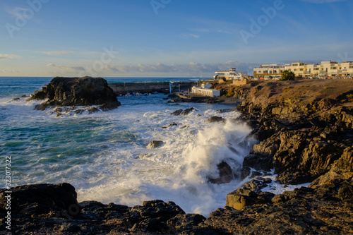 Large waves rolling into harbour entrance El Cotillo in the evening light