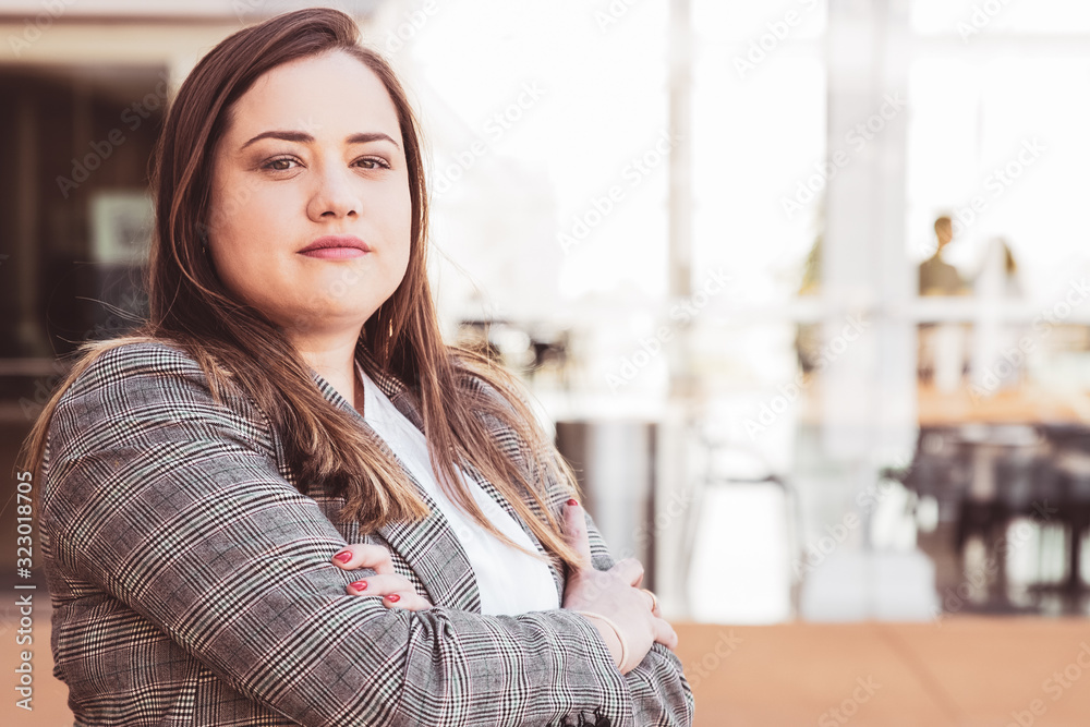 Confident business woman posing at camera outdoors. Lady looking at camera and standing with her arms crossed and blurred view in background. Business lady portrait concept. Confident business woman posing at camera outdoors. Lady looking at camera and standing with her arms crossed and blurred view in background. Business lady portrait concept.