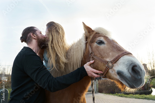 Loving couple man and woman blonde long hear Kissing Riding a Horse. Rural spring landscape. Family Relations and Valentine's Day Concept