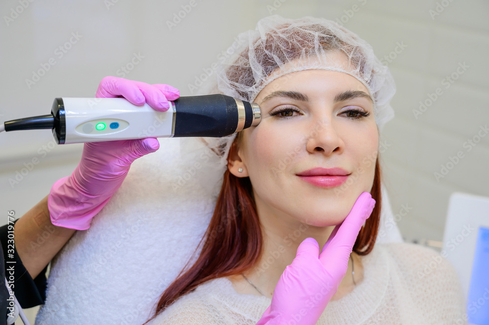 Portrait of a middle-aged woman receiving a non-surgical rejuvenation procedure at a cosmetologist. RF face lifting. Hardware facial massage. Portrait of a middle-aged woman receiving a non-surgical rejuvenation procedure at a cosmetologist. RF face lifting. Hardware facial massage.