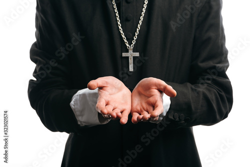 cropped view of catholic priest with silver cross on neck standing with cupped hands isolated on white