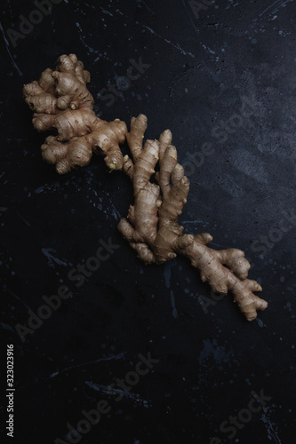 Fresh ginger root on a black distressed background