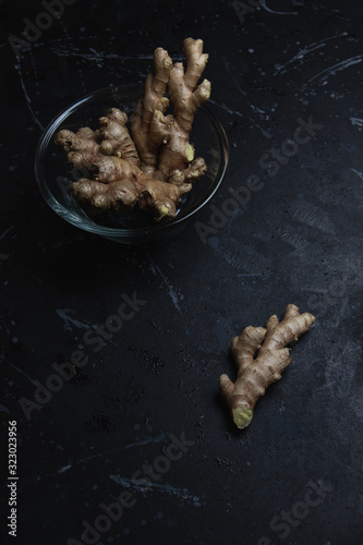 Ginger root in a glass bowl on a black distressed background