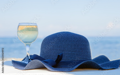 Foto A glass of white wine and a blue hat behind lagoon sea