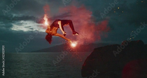 Extreme cliff jumping man backflipping off of an sea cliff with burning red hot flares at night, epic stuntman moments, people are awesome photo