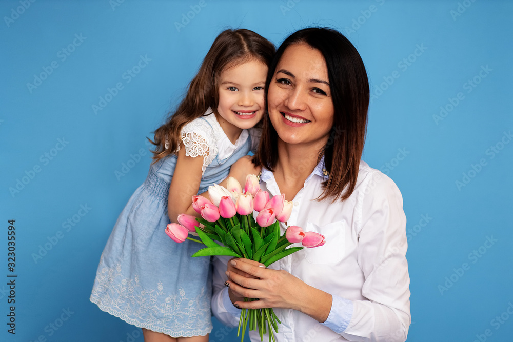 Portrait of happy smiling mother and daughter with a bouquet of tulips in their hands.