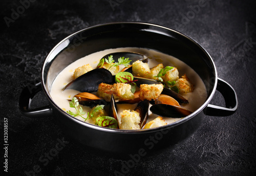 Mediterranean cuisine. Mussel soup in a bowl on the dark background. Background image, copy space
