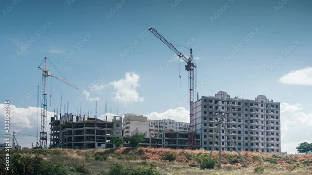 Cranes no longer work on Construction Site outdoor sunny day. tall cranes stand motionless against background floating clouds blue sky .work stopped result economic crisis. Cranes no longer work on Construction Site outdoor sunny day. tall cranes stand motionless against background floating clouds blue sky .work stopped result economic crisis.