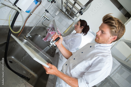 Obraz na plátně handsome employee doing dishes in commercial kitchen
