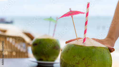 Travel summer vacation with girl holdes green fresh coconuts on the tropical beach.Honeymoon concept near beach.