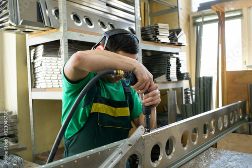 Foto Fitter working with a pistol type pneumatic drill preparing the part of body pla