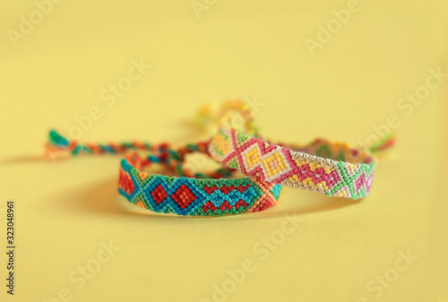 Two handmade homemade colorful natural woven bracelets of friendship isolated on wooden background, various colors