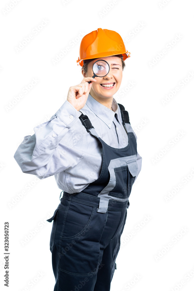 girl construction engineer examines something in a magnifying glass. Isolated girl construction engineer examines something in a magnifying glass. Isolated