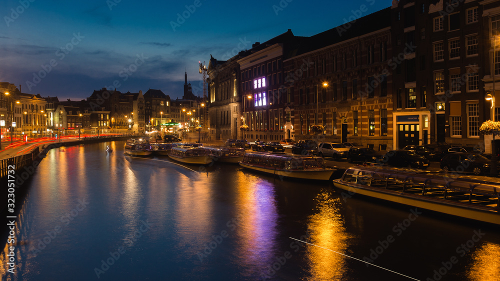 Amsterdam center at night. River and boats in the water.