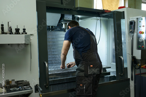 Worker fixing metal piece on the worktable of milling machine