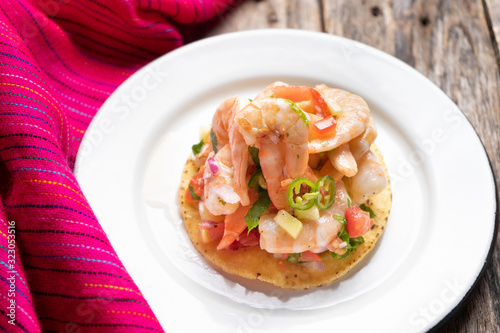 Mexican shrimp ceviche toast also called tostada on wooden background