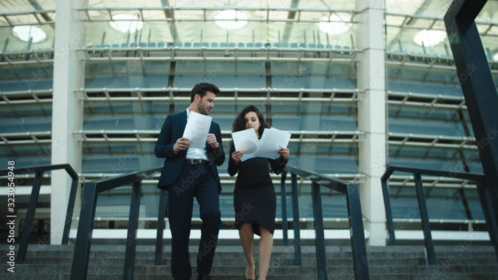 Business couple walking with documents. Couple discussing business papers Business couple walking with documents. Couple discussing business papers