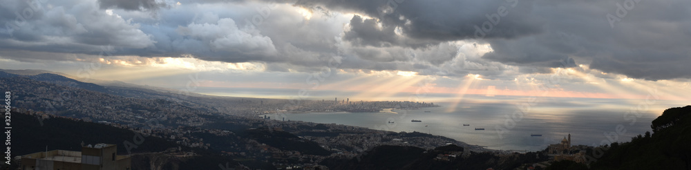 large panoramic view of Berut and Saint Georges Bay and lebanese shore between Beirut and Jounieh, shot from the mountain with dramatic sky and rays of light