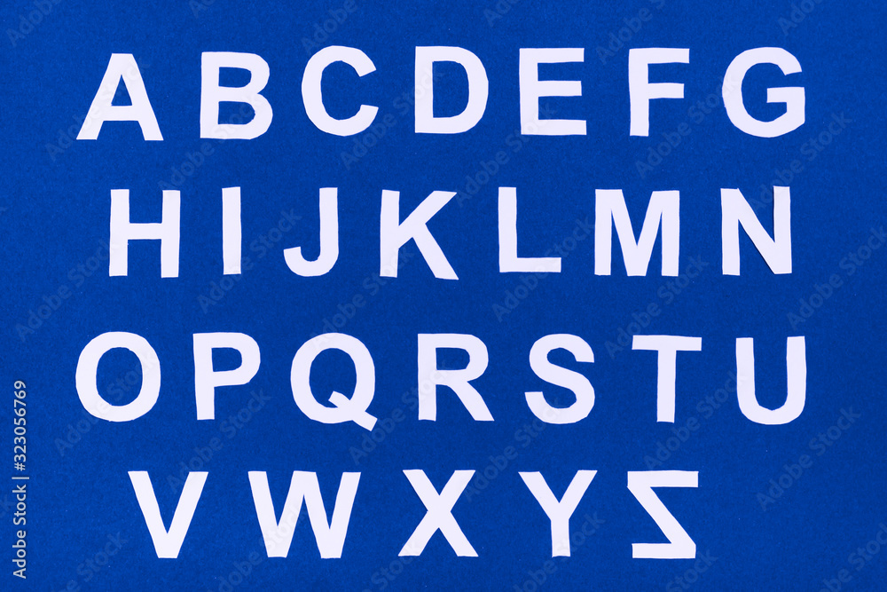 The letters of the English alphabet are cut out of blue cardboard on a white background