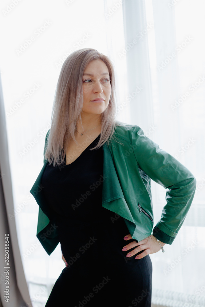 Blondie woman with long hair is posing in front of the window.