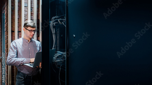 Obraz na plátně In the server room a technician/ It engineer/ hold the notebook