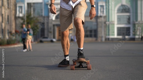 The skater's legs are accelerated on a longboard forward on a flat city road