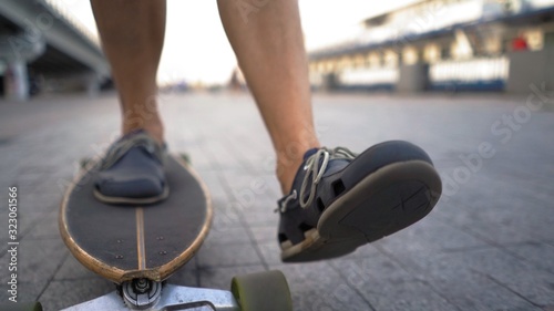 Light-Skinned Mid-Aged Man Gaining Speed On Skateboard Ahead Outdoor. © Svyatoslav Lypynskyy