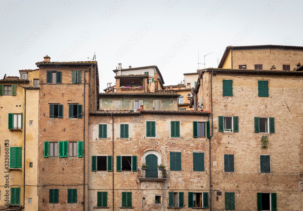 a view of typical brown houses with green windows in Siena city, Tuscany, Italy