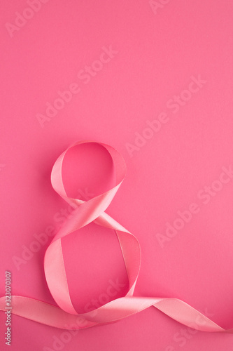 Holiday  background. Pink number eight ribbon on the pink surface. Location vertical. Top view. Copy space.