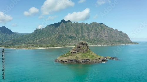 Sidways panning motion of the drone in aerial view of the Chinaman's hat with Kualoa beach and park with Ko'olau mountains in the background photo
