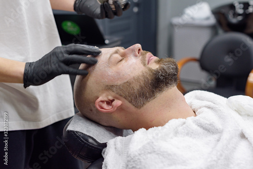 beard modeling in Barber shop, beard care for men, male beauty and care concept, applying the scrub to the face