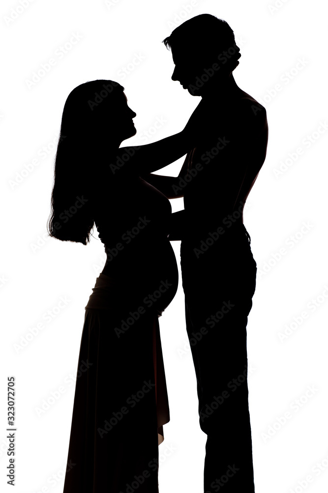 Silhouettes of two people men and a pregnant woman cuddling on a white background. The concept of warm family relationships. Copyspace Silhouettes of two people men and a pregnant woman cuddling on a white background. The concept of warm family relationships. Copyspace