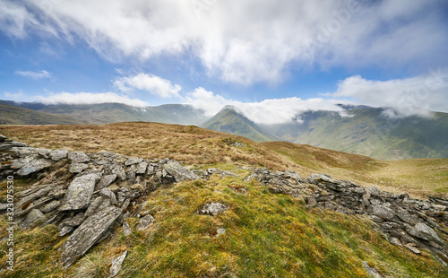 Scenic view of the mountain summits of The Knott, High Street, Thornthwaite, Gray Crag and a cloud covered Stony Cove Pike on a sunny day in the Lake District UK. photo